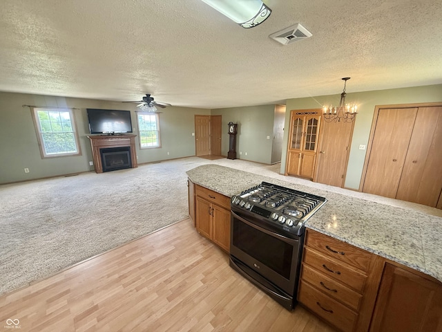 1687 Killion Ave, Seymour, IN 47274 - kitchen featuring gas stove, a ceiling fan, a textured ceiling, a fireplace, and a chandelier