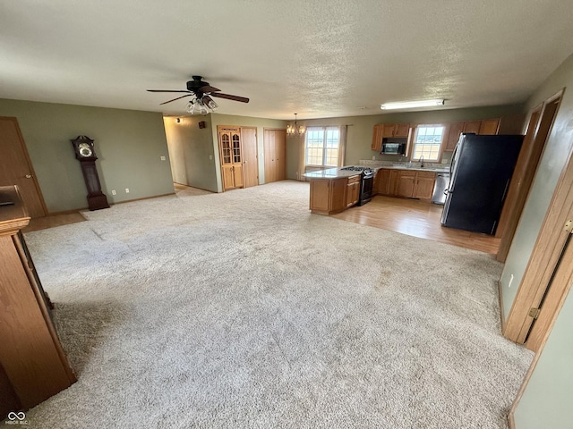 1687 Killion Ave, Seymour, IN 47274 - kitchen with stainless steel appliances, light colored carpet, brown cabinets, open floor plan, and a textured ceiling