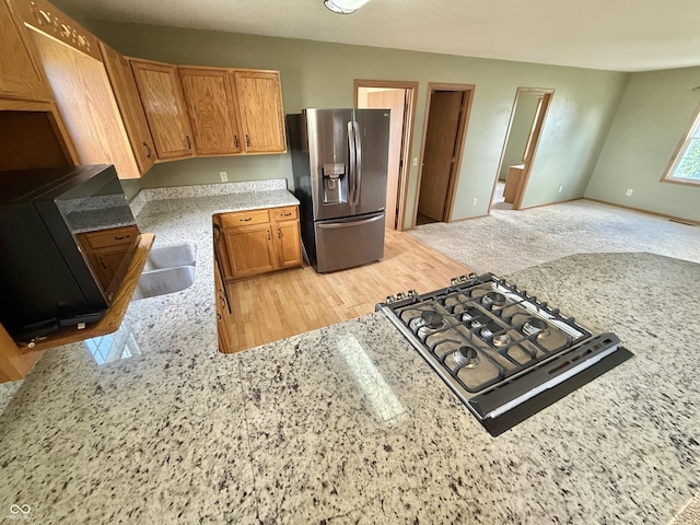 1687 Killion Ave, Seymour, IN 47274 - kitchen with stainless steel refrigerator with ice dispenser, cooktop, light stone counters, brown cabinets, and open floor plan
