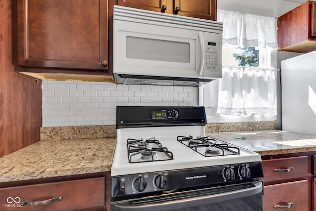 917 W Busby St, Lebanon, IN 46052 - kitchen with gas range oven, white microwave, backsplash, and light stone counters