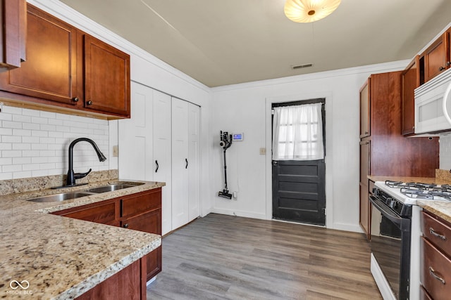 917 W Busby St, Lebanon, IN 46052 - kitchen featuring gas range, white microwave, decorative backsplash, and wood finished floors