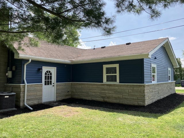 321 S 23rd St, Elwood, IN 46036 - rear view of property featuring stone siding, roof with shingles, and a lawn