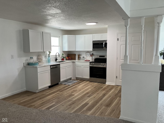 321 S 23rd St, Elwood, IN 46036 - kitchen featuring appliances with stainless steel finishes, light countertops, white cabinets, light wood-style flooring, and a textured ceiling