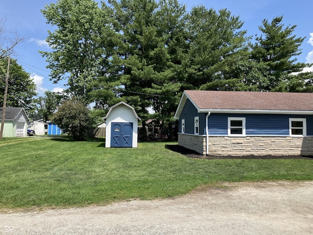 321 S 23rd St, Elwood, IN 46036 - view of side of property featuring stone siding, a shed, a yard, and roof with shingles