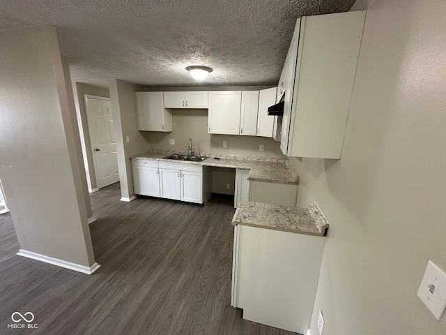 10316 Woodhaven Cir, Indianapolis, IN 46229 - kitchen featuring dark wood-style flooring, white cabinetry, a textured ceiling, under cabinet range hood, and light stone countertops
