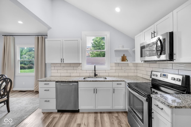 3035 Guilford Ave, Indianapolis, IN 46205 - kitchen with appliances with stainless steel finishes, plenty of natural light, lofted ceiling, light stone counters, and light wood-type flooring