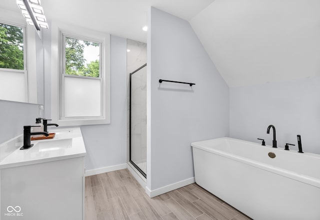 3035 Guilford Ave, Indianapolis, IN 46205 - bathroom featuring a freestanding bath, a shower stall, double vanity, wood finished floors, and vaulted ceiling