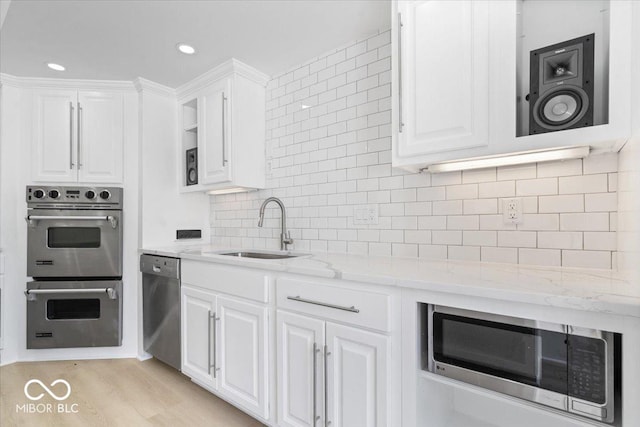 12208 Island Dr, Indianapolis, IN 46256 - kitchen with stainless steel appliances, white cabinetry, decorative backsplash, light stone countertops, and light wood finished floors
