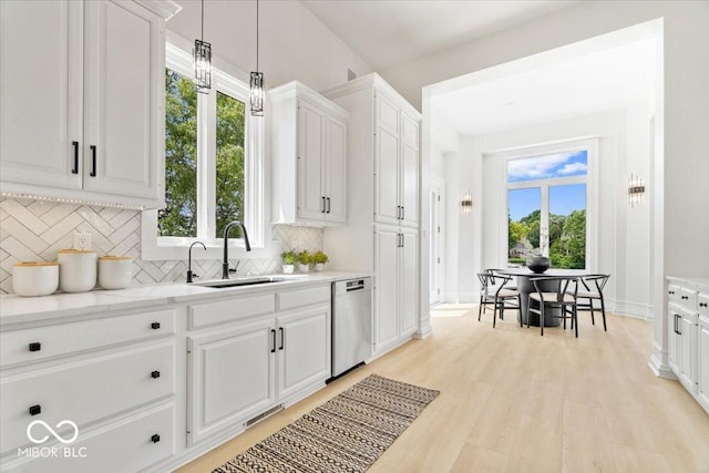 12208 Island Dr, Indianapolis, IN 46256 - kitchen with dishwasher, backsplash, white cabinets, light wood finished floors, and pendant lighting