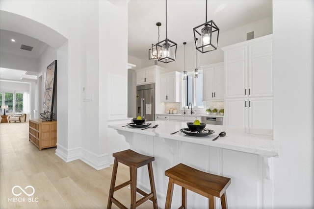 12208 Island Dr, Indianapolis, IN 46256 - kitchen featuring stainless steel built in refrigerator, a breakfast bar area, light wood-style flooring, arched walkways, and white cabinets