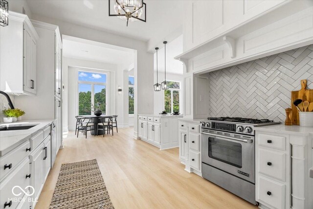 12208 Island Dr, Indianapolis, IN 46256 - kitchen with stainless steel appliances, a chandelier, decorative backsplash, white cabinets, and light stone counters