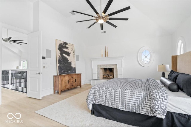 12208 Island Dr, Indianapolis, IN 46256 - bedroom featuring high vaulted ceiling, multiple windows, wood finished floors, a fireplace, and a ceiling fan