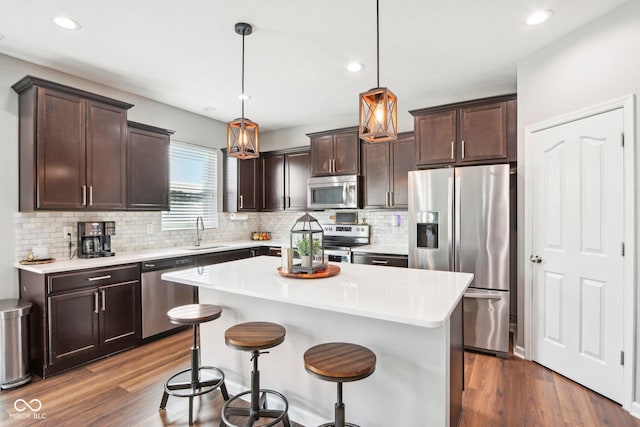 14453 Glapthorn Rd, Fishers, IN 46037 - kitchen with appliances with stainless steel finishes, dark brown cabinets, decorative backsplash, a center island, and light countertops