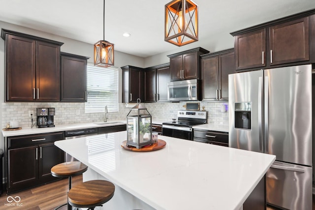 14453 Glapthorn Rd, Fishers, IN 46037 - kitchen with appliances with stainless steel finishes, backsplash, dark brown cabinets, light countertops, and pendant lighting