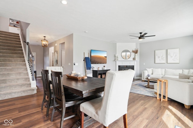 14453 Glapthorn Rd, Fishers, IN 46037 - dining space with stairway, wood finished floors, a ceiling fan, a fireplace, and a chandelier