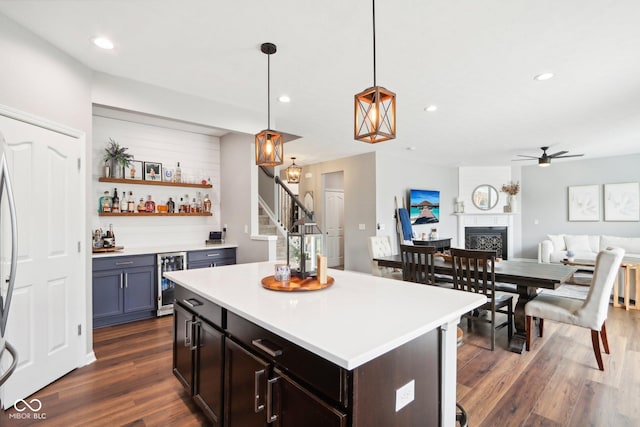 14453 Glapthorn Rd, Fishers, IN 46037 - kitchen featuring a fireplace, dark wood-style floors, light countertops, a ceiling fan, and beverage cooler