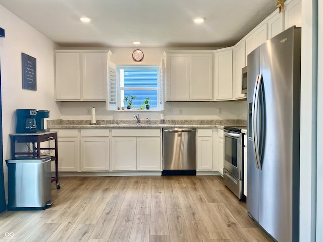 213 Drewood Dr, Trafalgar, IN 46181 - kitchen featuring appliances with stainless steel finishes, white cabinets, light stone counters, light wood-style flooring, and recessed lighting