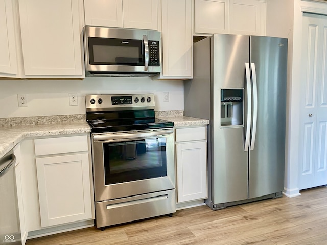 213 Drewood Dr, Trafalgar, IN 46181 - kitchen with stainless steel appliances, light wood-style flooring, light countertops, and white cabinets