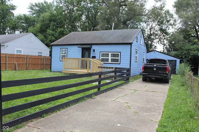 3201 W 22nd St, Indianapolis, IN 46222 - bungalow with roof with shingles, a fenced front yard, concrete driveway, and a detached garage