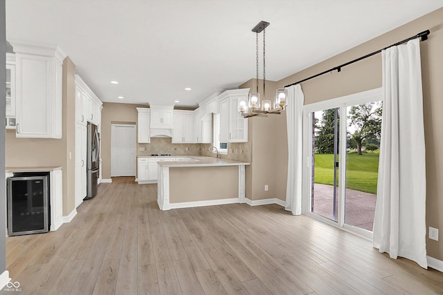 3345 Kilkenny Cir, Carmel, IN 46032 - kitchen with wine cooler, stainless steel refrigerator, light countertops, a peninsula, and light wood-type flooring