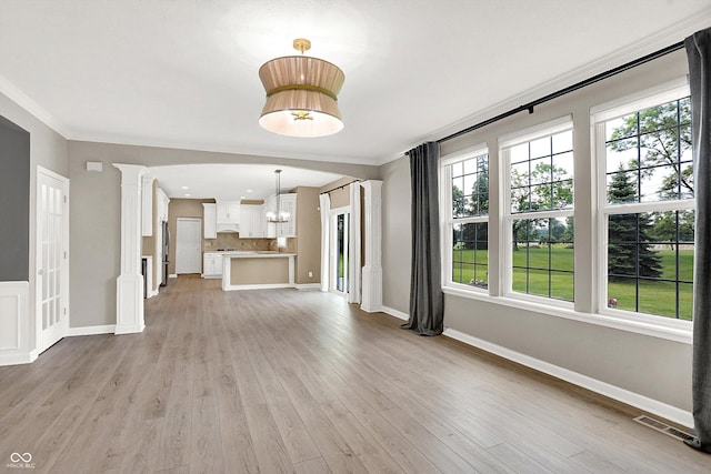3345 Kilkenny Cir, Carmel, IN 46032 - unfurnished living room with decorative columns, a chandelier, light wood-type flooring, and ornamental molding