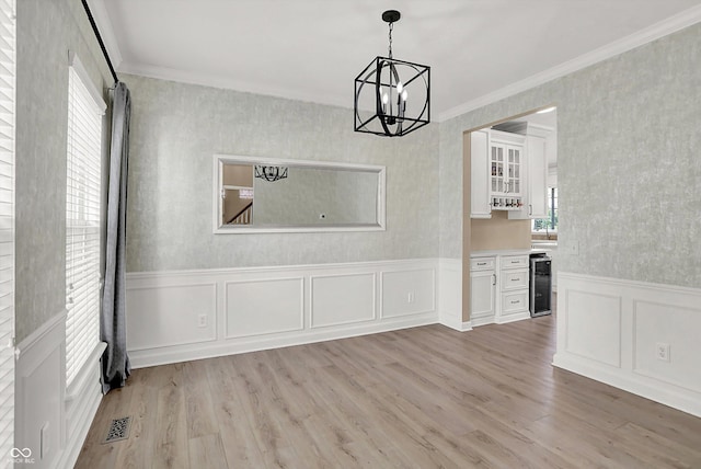 3345 Kilkenny Cir, Carmel, IN 46032 - unfurnished dining area featuring wine cooler, a chandelier, light wood-style floors, crown molding, and a decorative wall