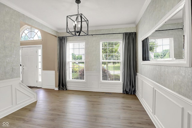 3345 Kilkenny Cir, Carmel, IN 46032 - unfurnished dining area featuring wainscoting, crown molding, a chandelier, healthy amount of natural light, and a decorative wall
