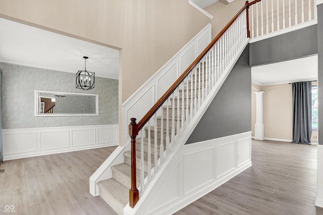 3345 Kilkenny Cir, Carmel, IN 46032 - staircase featuring a decorative wall, wood finished floors, a high ceiling, wainscoting, and a chandelier