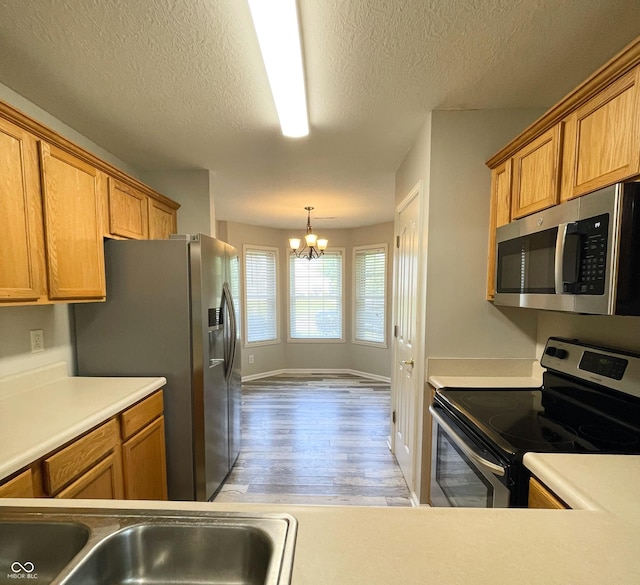 1173 Carlton Ct, Greenwood, IN 46143 - kitchen featuring appliances with stainless steel finishes, a chandelier, light wood-type flooring, a textured ceiling, and light countertops