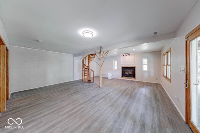 8635 S Providence Dr, Nineveh, IN 46164 - unfurnished living room with wood finished floors, stairs, a glass covered fireplace, and concrete block wall