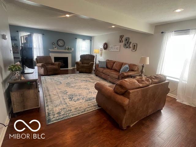 2231 Abbey St, Brownsburg, IN 46112 - living room featuring wood finished floors, a fireplace with flush hearth, beam ceiling, and recessed lighting