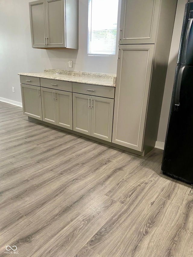 3464 N Bancroft St, Indianapolis, IN 46218 - kitchen with fridge with ice dispenser, gray cabinetry, light wood-style floors, and light stone counters