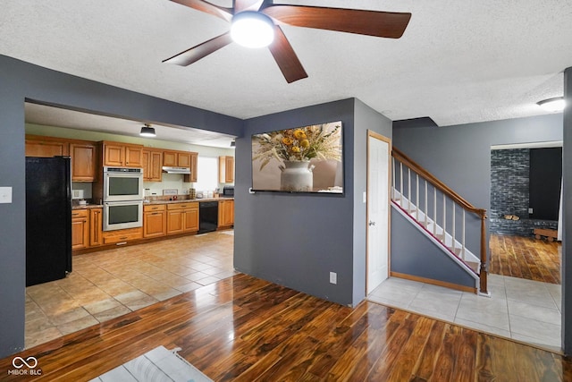 13041 S Finer St, Pimento, IN 47866 - kitchen with black appliances, light wood finished floors, brown cabinets, under cabinet range hood, and ceiling fan