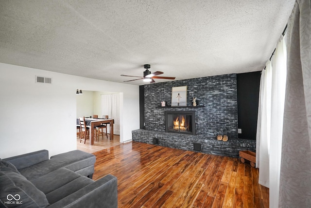 13041 S Finer St, Pimento, IN 47866 - living area featuring wood finished floors, a textured ceiling, ceiling fan, and a brick fireplace