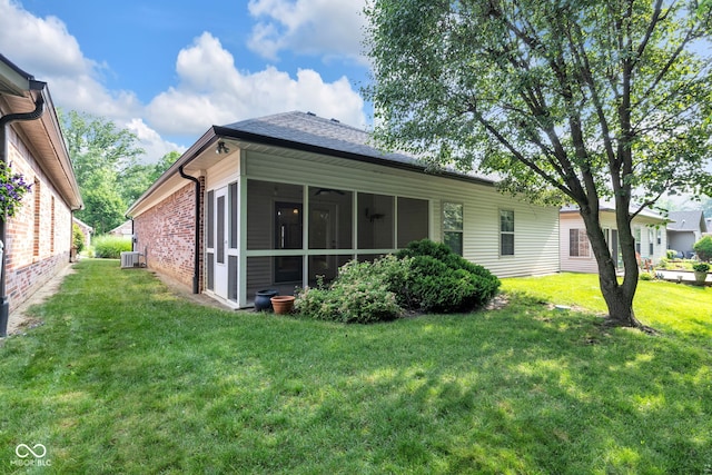 9735 Woodsong Ln, Indianapolis, IN 46229 - rear view of house with a sunroom, a lawn, a shingled roof, and brick siding