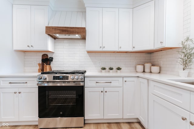 14407 Bryn Mawr Dr, Fishers, IN 46038 - kitchen featuring stainless steel gas range, custom range hood, light countertops, and white cabinetry