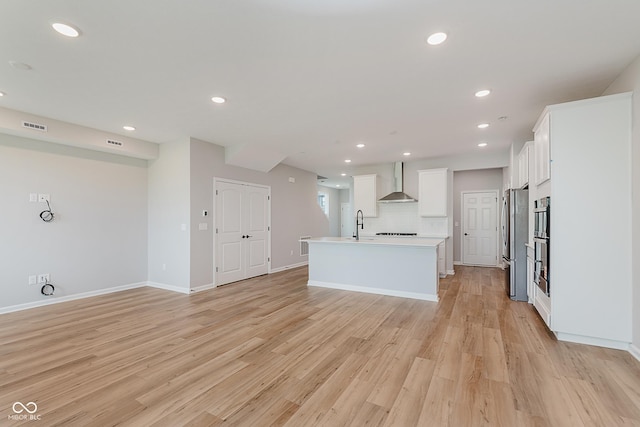 9751 Behner Dr, Fishers, IN 46250 - kitchen with wall chimney range hood, appliances with stainless steel finishes, a center island with sink, white cabinets, and light countertops