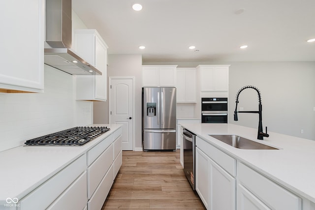 9751 Behner Dr, Fishers, IN 46250 - kitchen featuring appliances with stainless steel finishes, wall chimney range hood, white cabinets, light wood finished floors, and light countertops