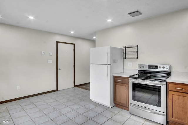 168 Midway Ct S, Hope, IN 47246 - kitchen featuring electric range, freestanding refrigerator, light countertops, brown cabinetry, and light tile patterned flooring