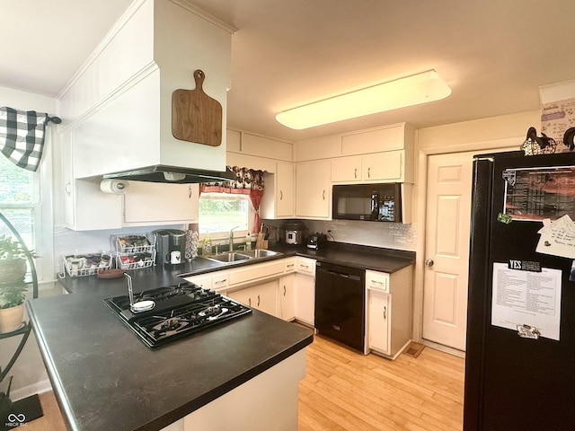 2615 Alexandria Pike, Anderson, IN 46012 - kitchen with black appliances, a peninsula, dark countertops, light wood-style flooring, and white cabinets