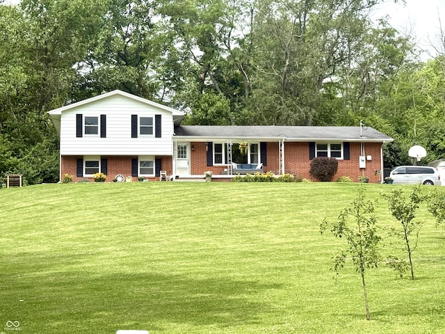 2615 Alexandria Pike, Anderson, IN 46012 - split level home featuring a front lawn, brick siding, a porch, and view of wooded area