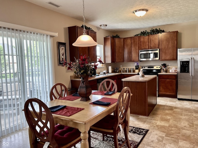 13859 Keams Dr, Fishers, IN 46038 - kitchen featuring appliances with stainless steel finishes, a kitchen island, light countertops, pendant lighting, and a textured ceiling