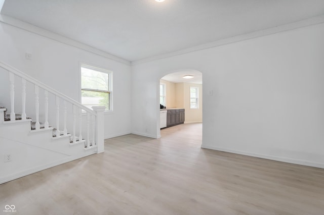 321 W Broad St, Spiceland, IN 47385 - unfurnished living room featuring arched walkways, light wood-style flooring, healthy amount of natural light, stairway, and ornamental molding