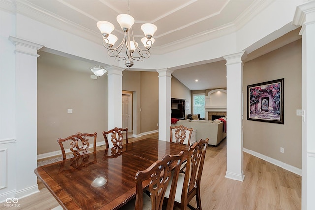 11074 Galley Way, Fishers, IN 46040 - dining area featuring a fireplace, light wood-style flooring, decorative columns, ornamental molding, and a tray ceiling