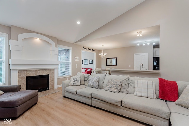 11074 Galley Way, Fishers, IN 46040 - living room featuring light wood-style flooring, plenty of natural light, a chandelier, lofted ceiling, and a tiled fireplace