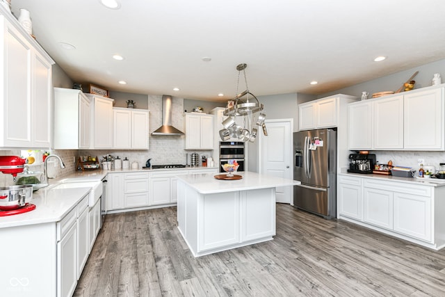 9053 Fitzgerald Dr, Indianapolis, IN 46239 - kitchen featuring appliances with stainless steel finishes, wall chimney range hood, backsplash, light countertops, and a center island