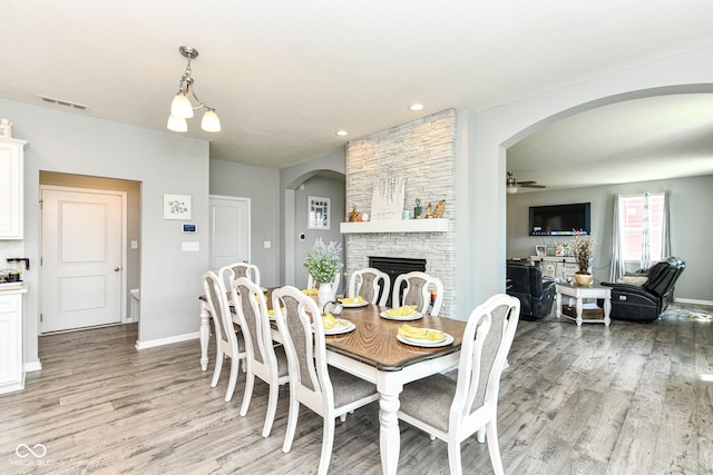 9053 Fitzgerald Dr, Indianapolis, IN 46239 - dining space featuring arched walkways, light wood finished floors, a fireplace, ceiling fan, and recessed lighting