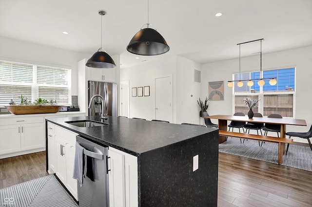 2720 Guilford Ave, Indianapolis, IN 46205 - kitchen featuring stainless steel appliances, wood finished floors, dark countertops, white cabinets, and a kitchen island with sink