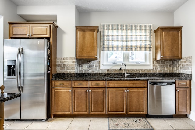 4904 N Washington Blvd, Indianapolis, IN 46205 - kitchen with stainless steel appliances, brown cabinets, decorative backsplash, light tile patterned flooring, and dark stone counters