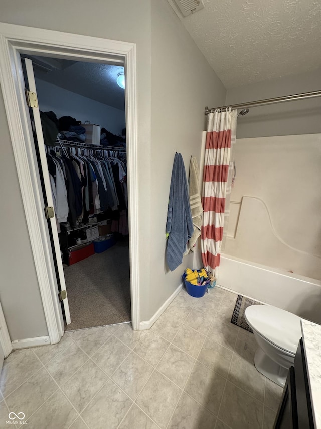 6027 Moonseed Cir, Indianapolis, IN 46203 - bathroom with a textured ceiling, shower / tub combo with curtain, a walk in closet, tile patterned floors, and vanity